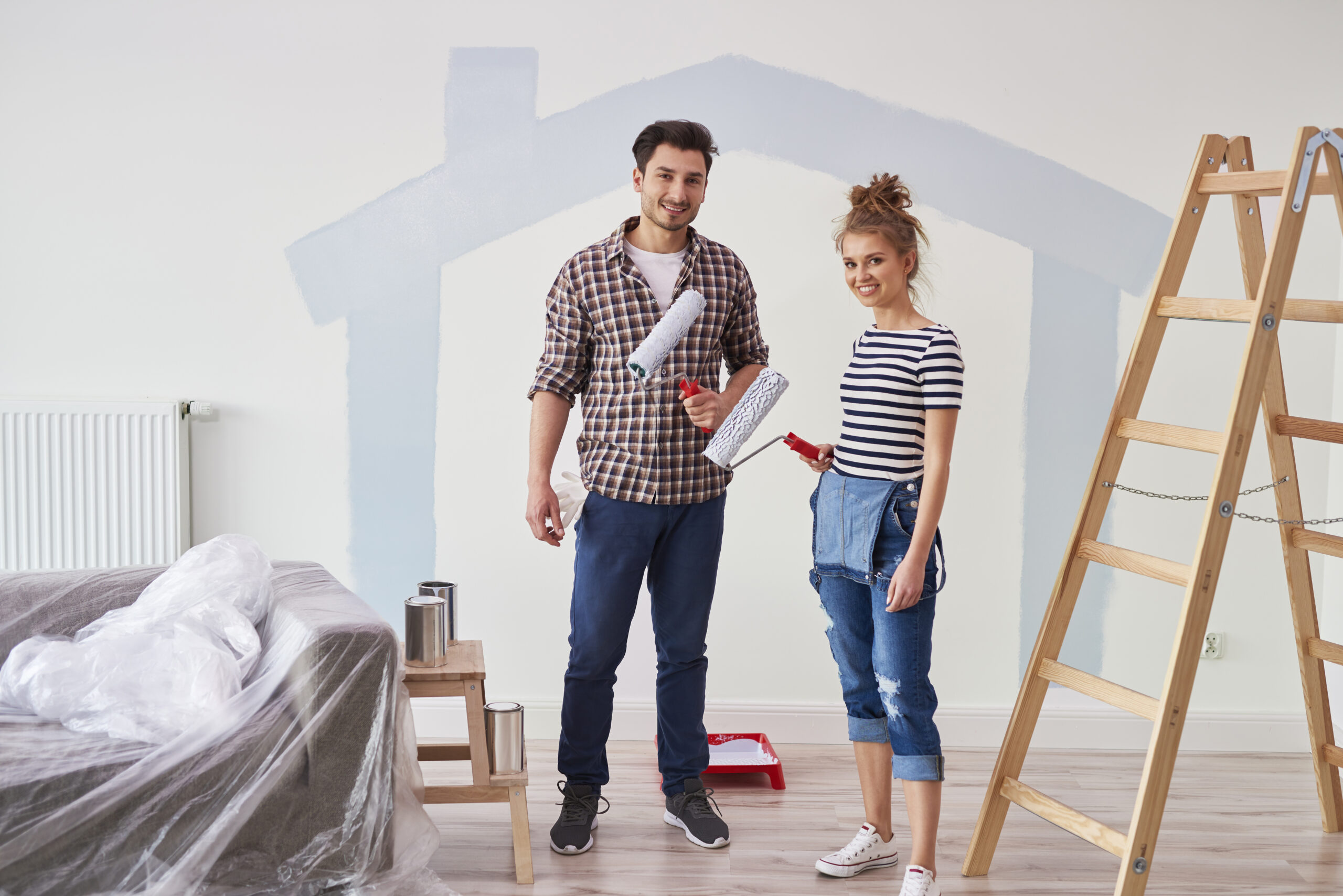 portrait of couple painting the interior wall in new apartment